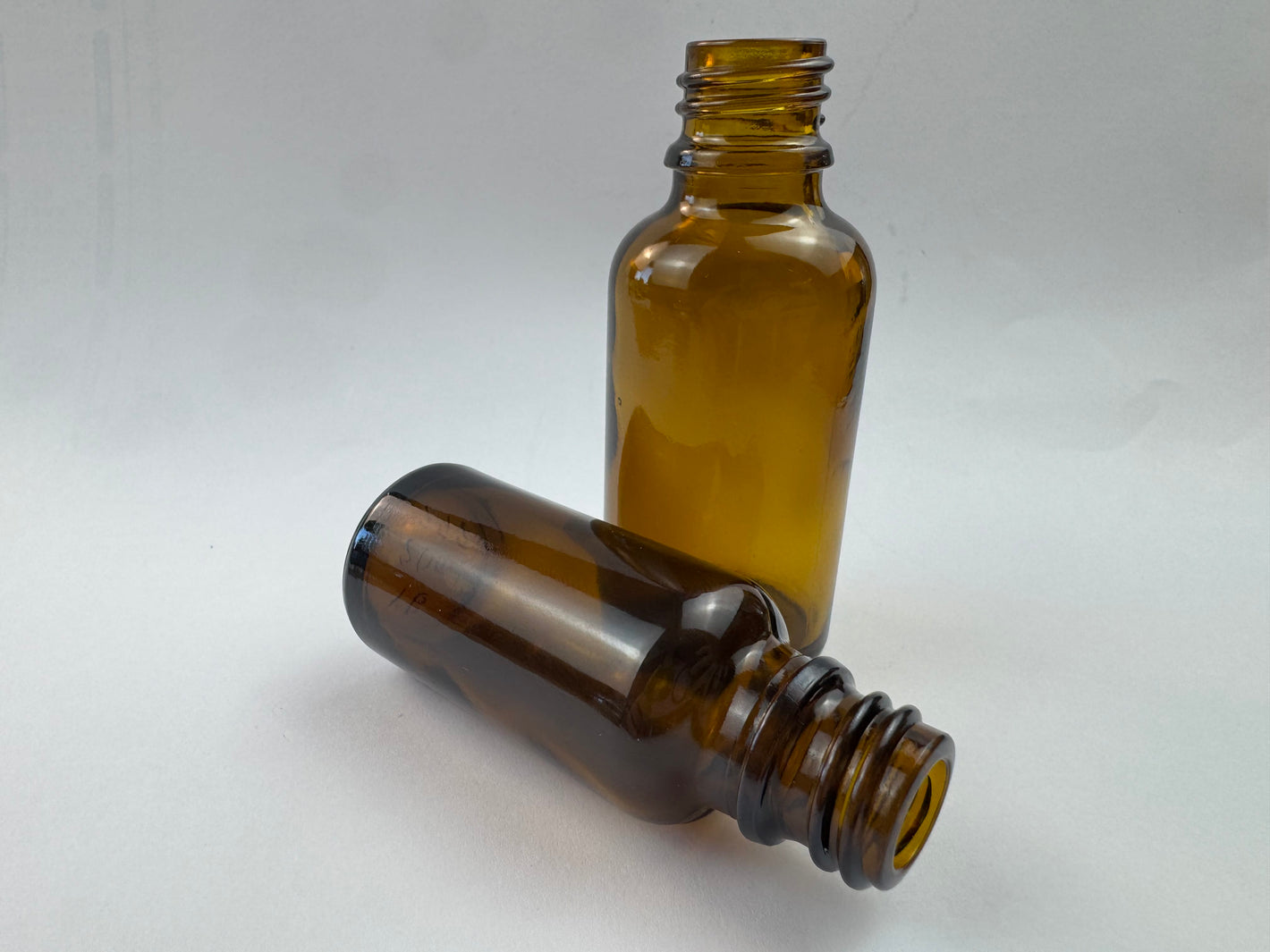 Two empty 100ml amber glass dropper bottles with threaded necks, displayed against a clean white background.