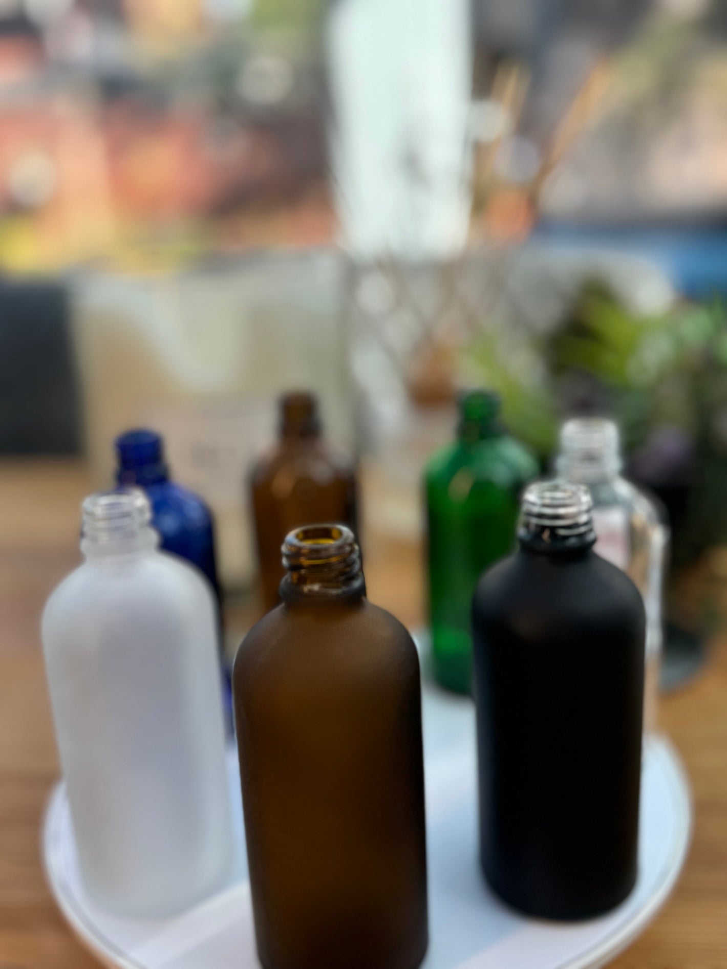 Assorted frosted glass dropper bottles in amber, black, white, blue, and green on a white tray.