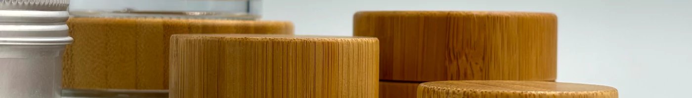Close-up of glass jars with natural bamboo lids and a silver tin, showcasing a minimalist, sustainable storage style.