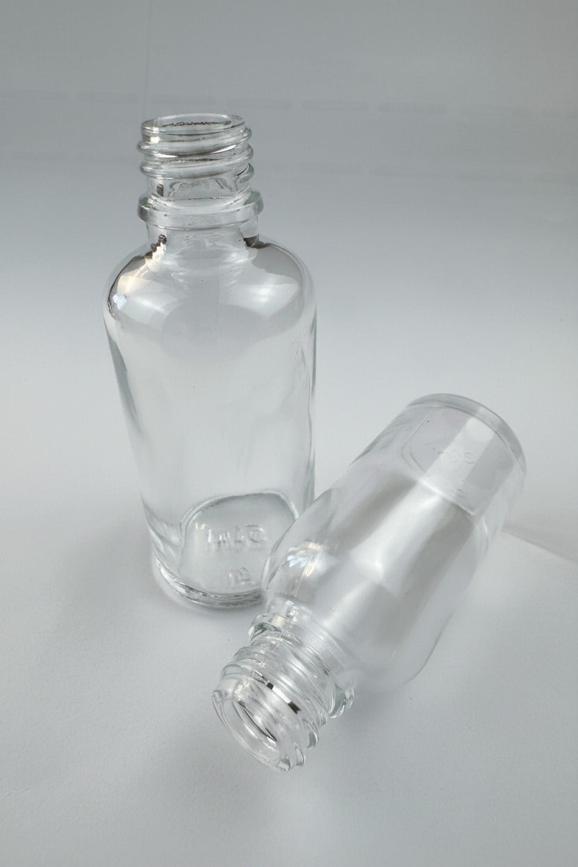 Two empty, clear glass dropper bottles with threaded necks arranged on a clean white background.