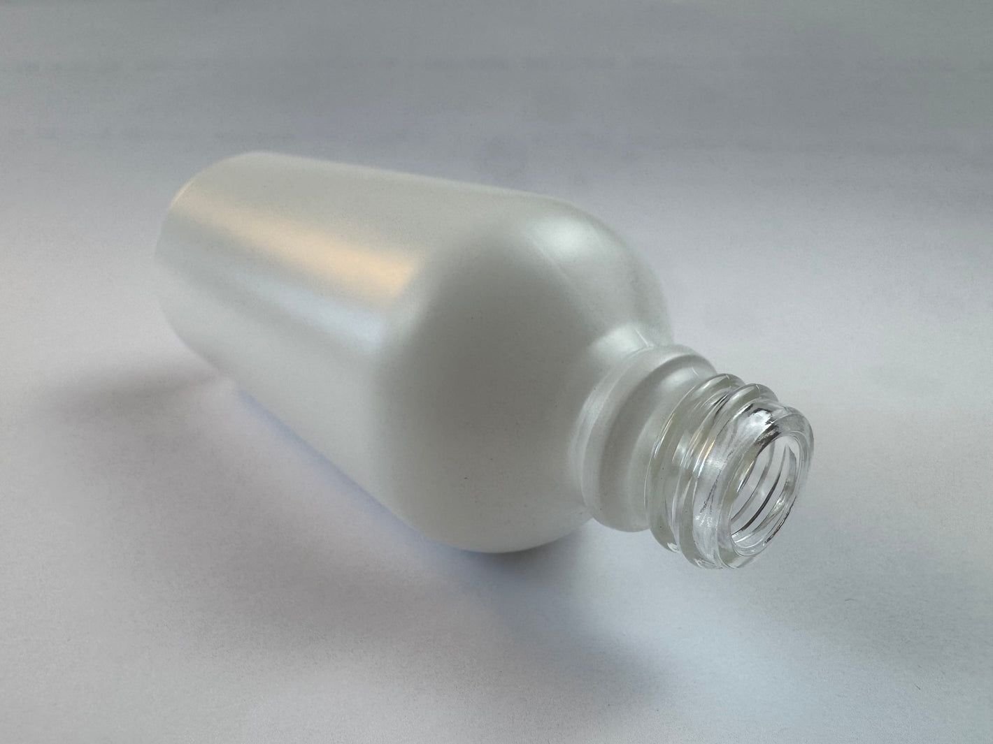 Elegant matte white glass dropper bottle lying on its side against a clean, minimalist background.