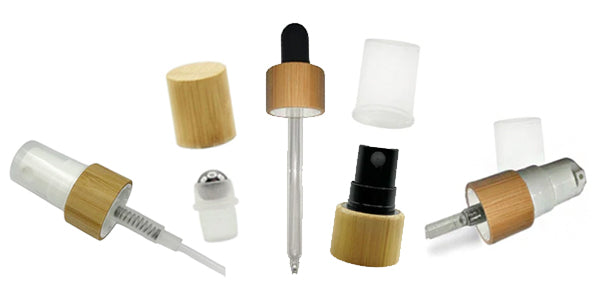Assorted bamboo cosmetic closures including spray pumps, droppers, and roller balls with natural wood finishes.